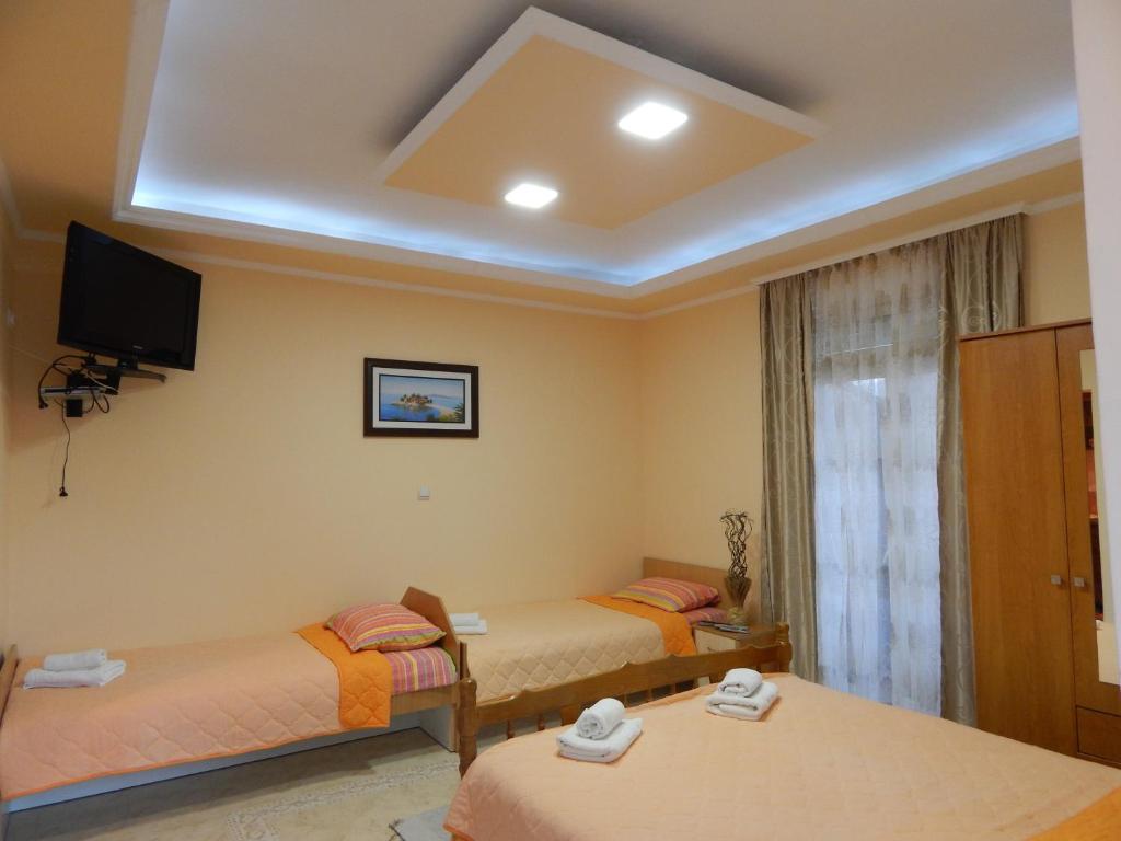 蒂瓦特Apartments Klakor的客房设有两张床和天花板上的电视。