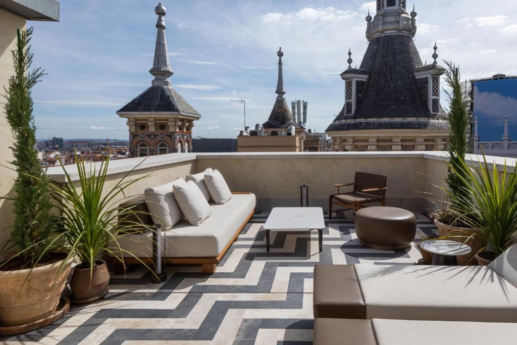 马德里JW Marriott Hotel Madrid的大楼内设有一个带沙发和桌子的屋顶露台