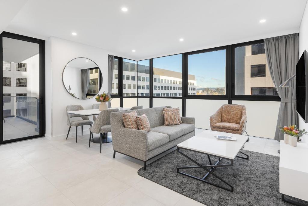 堪培拉Meriton Suites Canberra的客厅配有沙发、椅子和桌子