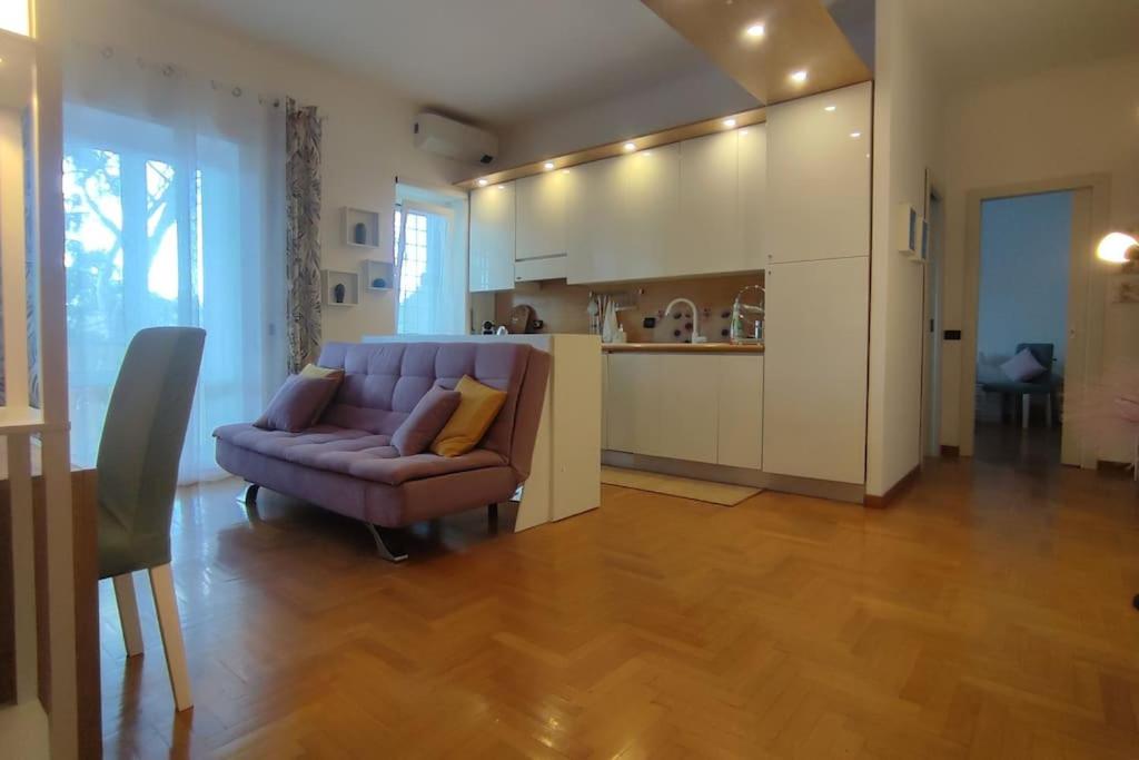 罗马Gastaldi House, EUR Mostacciano, delizioso flat的一间带紫色沙发的客厅和一间厨房