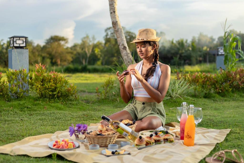 马希延格讷Elephyard Retreat的坐在野餐毯上的戴帽子的女人