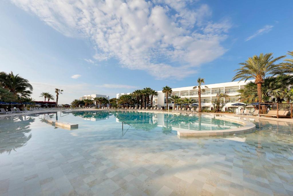 普拉亚登博萨Grand Palladium Palace Ibiza Resort & Spa- All Inclusive的一座棕榈树大型游泳池和一座建筑