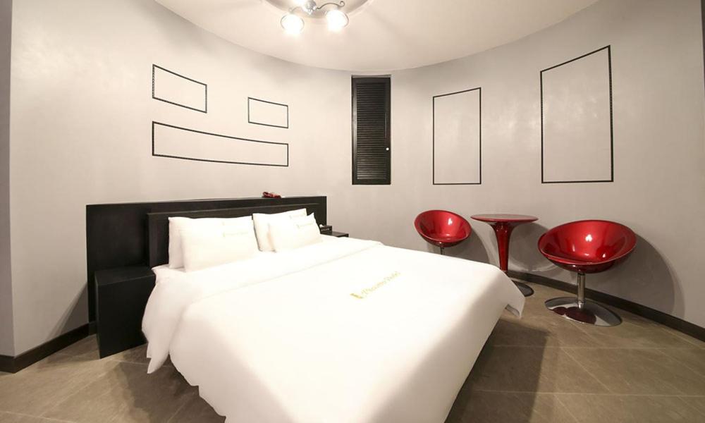 坡州市Paju Picasso的一间卧室配有白色的床和两张红色椅子