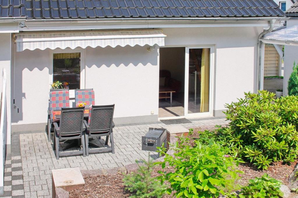 吕本瑙Ferienhaus Herz的房屋前设有带椅子和烧烤设施的庭院。