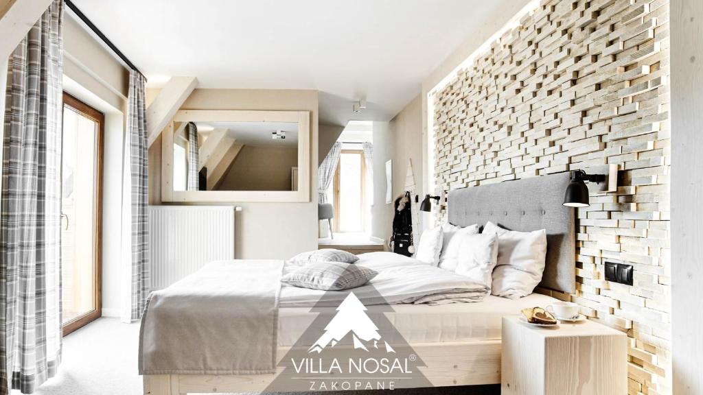 扎科帕内VILLA NOSAL - Zakopane的一间卧室设有一张大床和砖墙