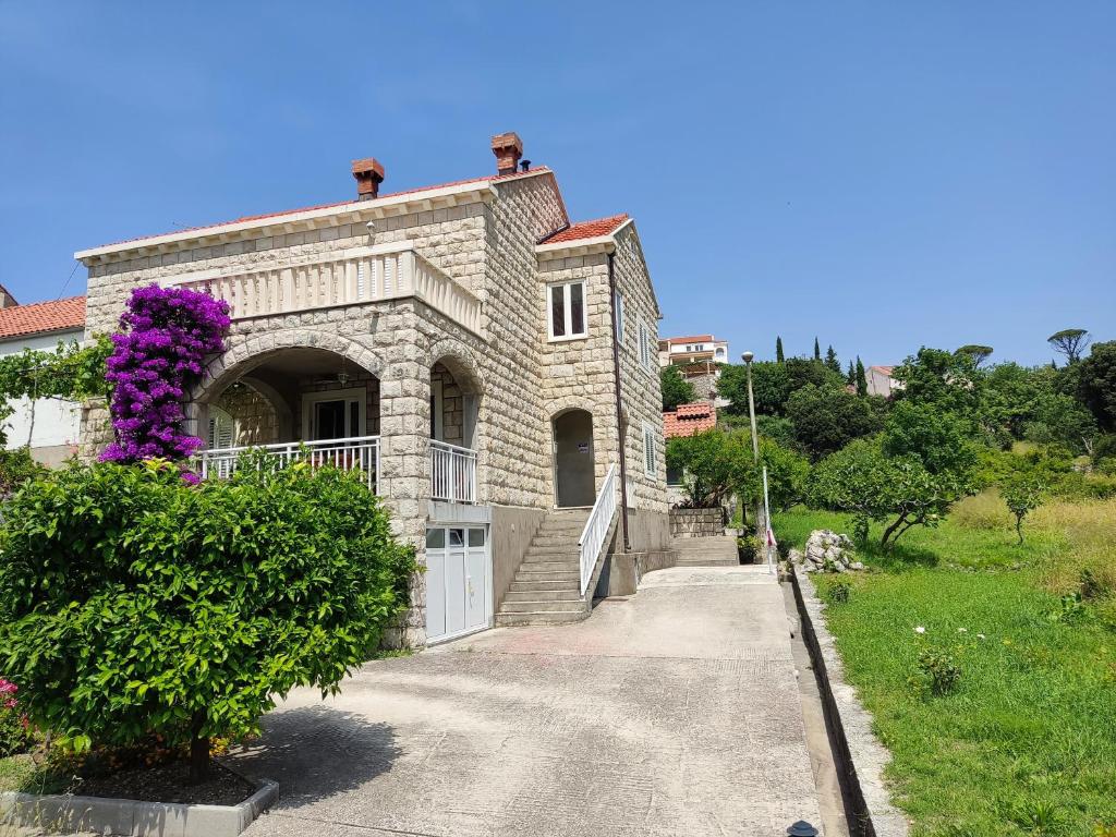 斯拉诺Guest House Franica & Pero Lobrovic的一座带门和紫色花卉的大型石屋
