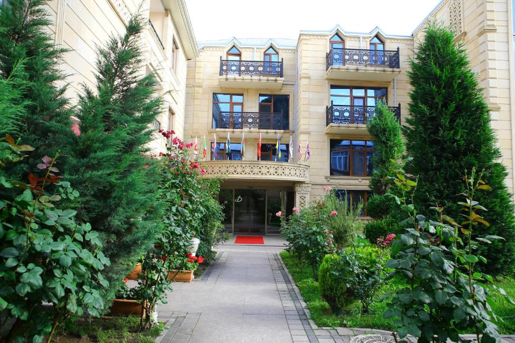甘贾Deluxe Hotel Ganja的前面有树木和植物的建筑