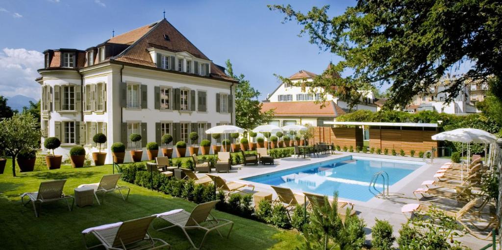 洛桑英格兰旅馆和公寓的一座大房子,在庭院里设有一个游泳池