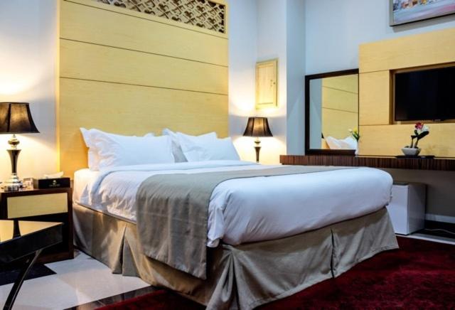 多哈多哈丹思提尼酒店的一间卧室设有一张大床和一个大镜子