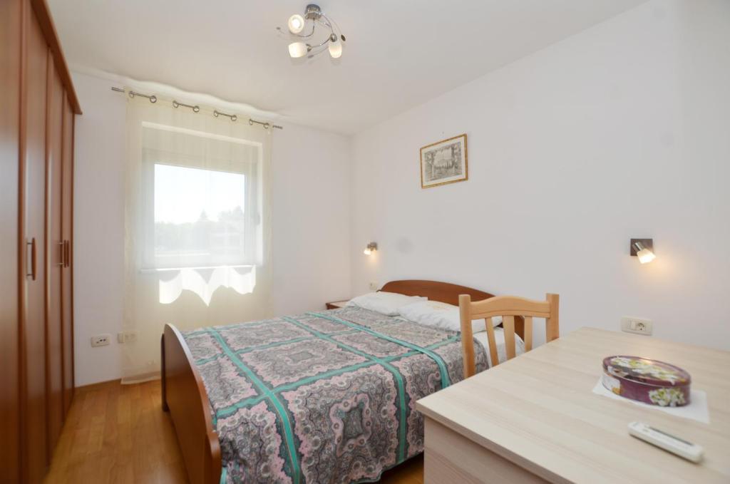 罗维尼Miro Apartment的一间卧室配有一张床、一张桌子和一个窗户。