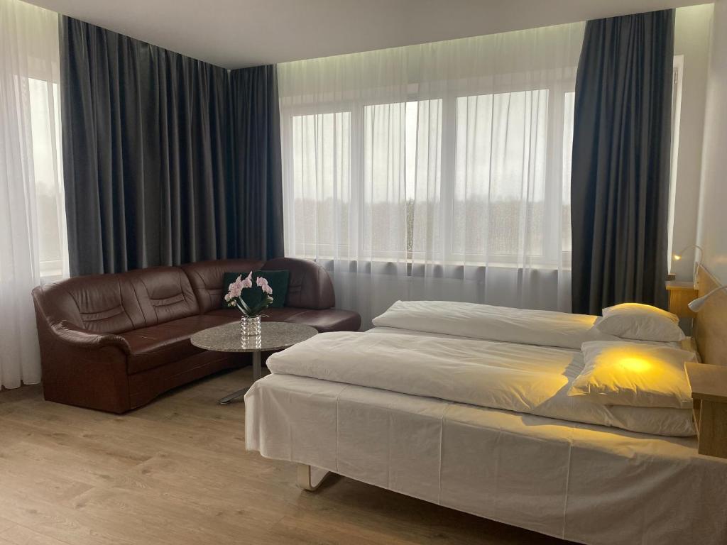 陶拉格Viešbutis Banga的一间卧室配有一张床、一张沙发和一张桌子