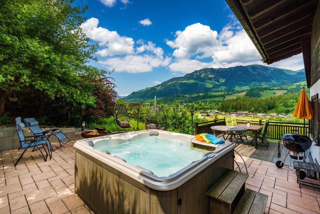 基茨比厄尔Chalet Mora-lodge by Alpine Host Helpers的庭院内的一个热水浴池,享有山脉背景