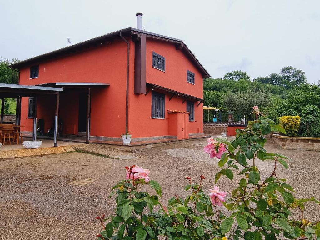 VignanelloCountry house Dolce Nocciola的前面有粉红色花的红色房子