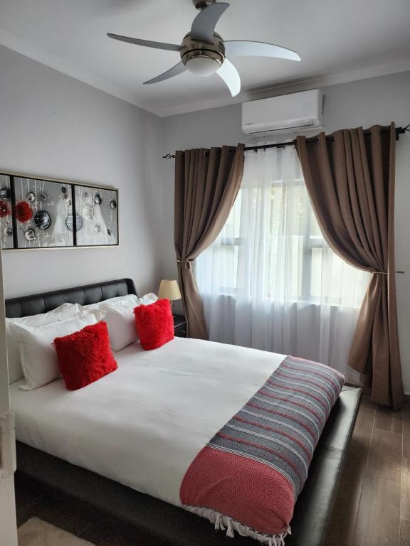 哈博罗内Sarona Studio A103的卧室配有带红色枕头的大型白色床
