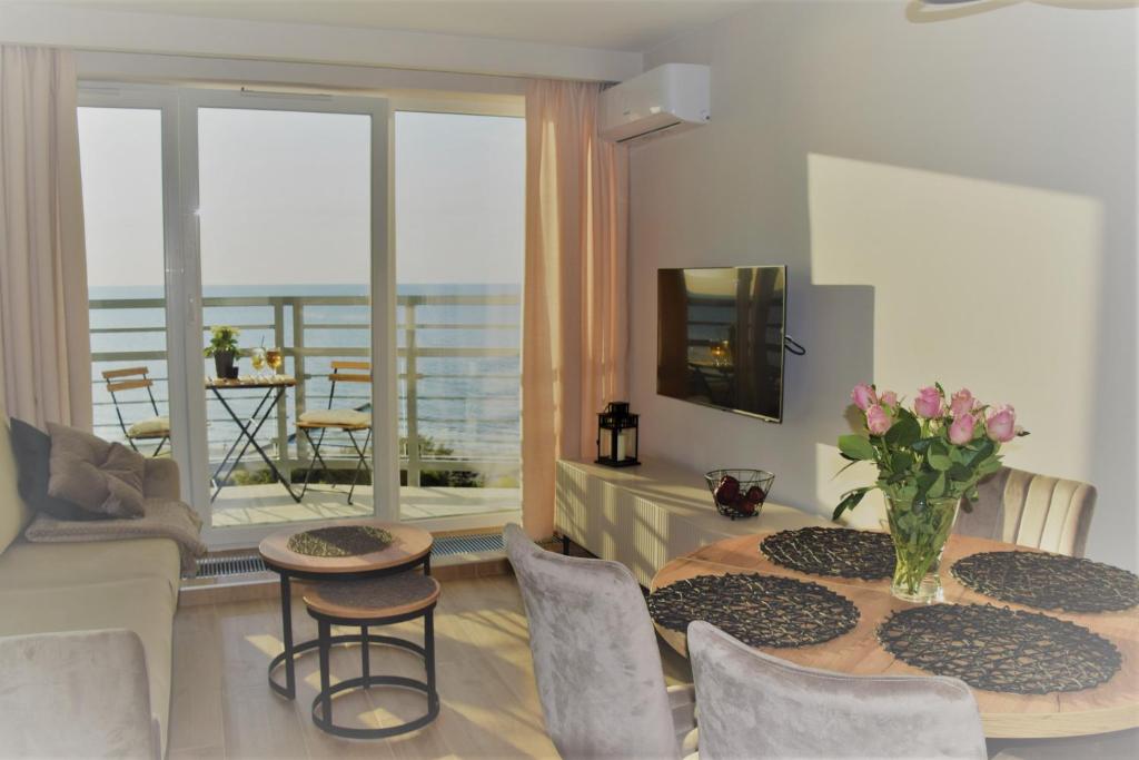 济夫努夫M&M Apartament Dziwnówek (z widokiem na morze)的一间带桌椅的客厅和一个阳台