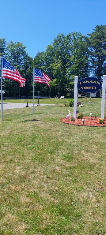 CanaanCanaan Motel的两个美国国旗在标志旁的田野