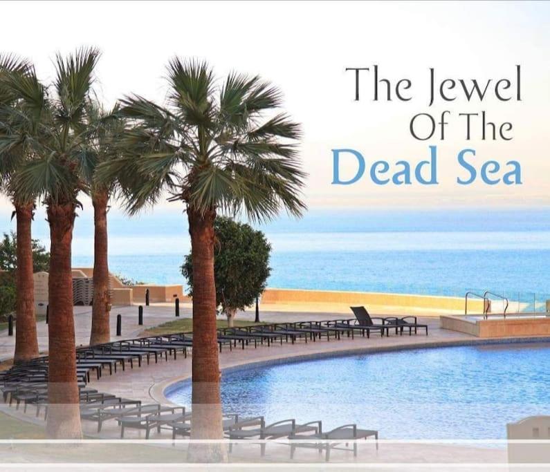 索瓦马Dead Sea Jordan Sea View Samarah Resort Traveler Award 2024 winner的海滩旁的棕榈树游泳池