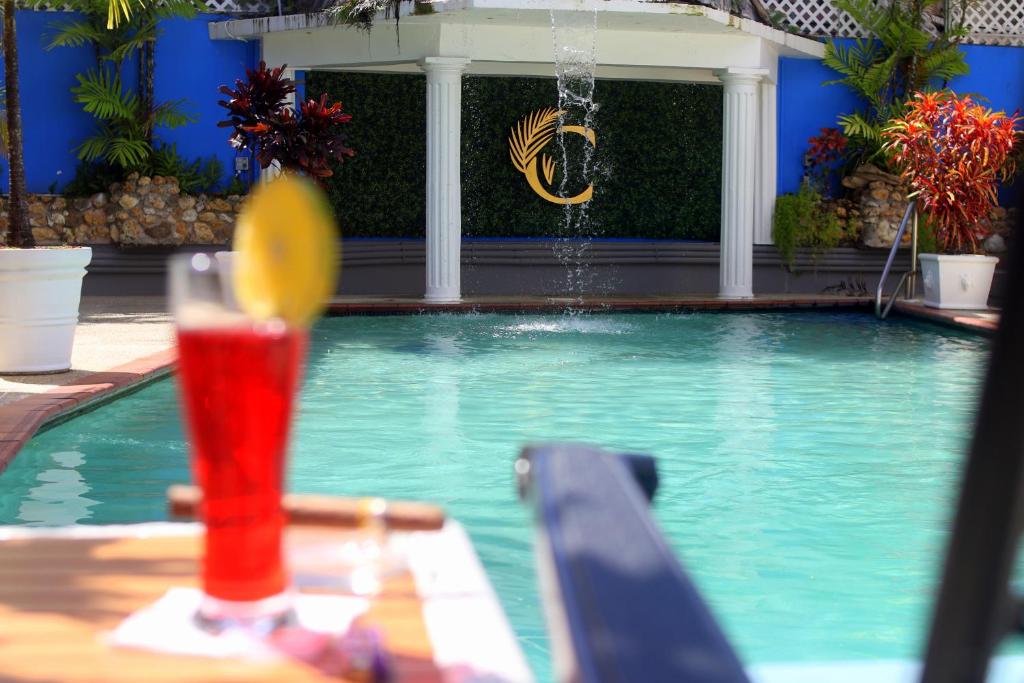 西班牙港The Chancellor Hotel的坐在游泳池旁的桌子上喝一杯