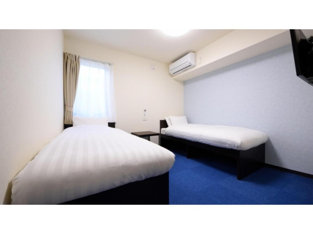 气仙沼市La'gent Inn Kesennuma - Vacation STAY 85809v的小房间设有两张床和窗户