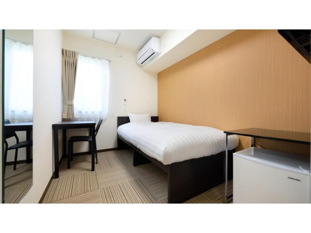 气仙沼市La'gent Inn Kesennuma - Vacation STAY 85811v的一间卧室配有一张床、一张桌子和一张桌子