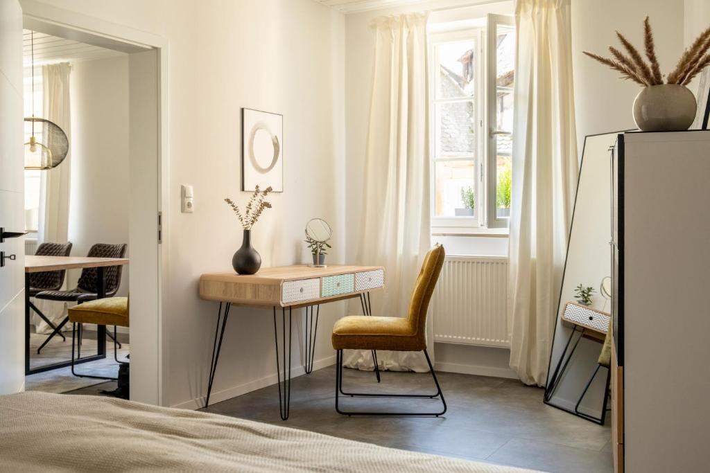 拜罗伊特Stilvolles Apartment in Bayreuther Fußgängerzone的卧室配有书桌和椅子,位于窗户前