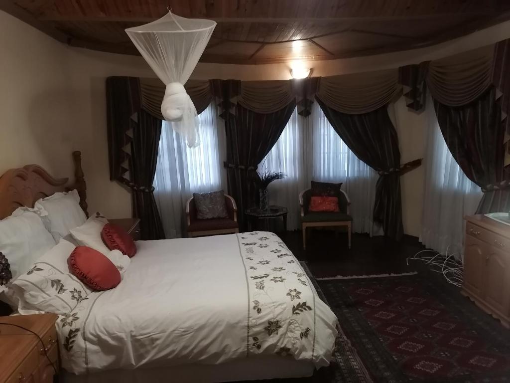 LobatseTjibelu's Nest Guest Home的一间卧室配有带白色床单和红色枕头的床。