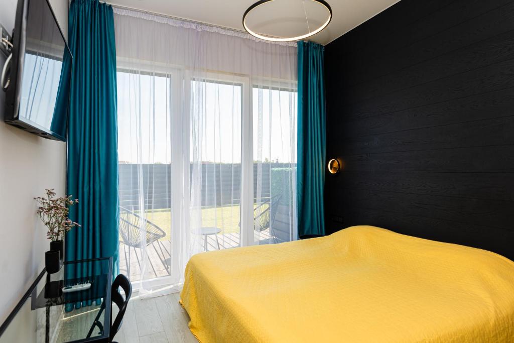 帕兰加2NIGHT in Šventoji的一间卧室设有一张黄色的床和一个大窗户