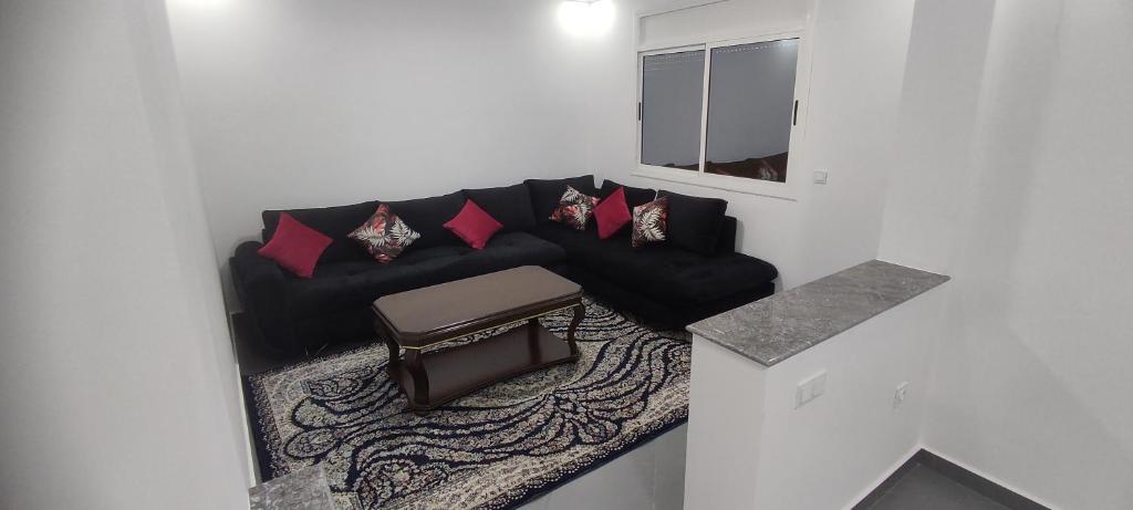 SelouaneLogement familial 2的客厅配有带红色枕头的黑色沙发
