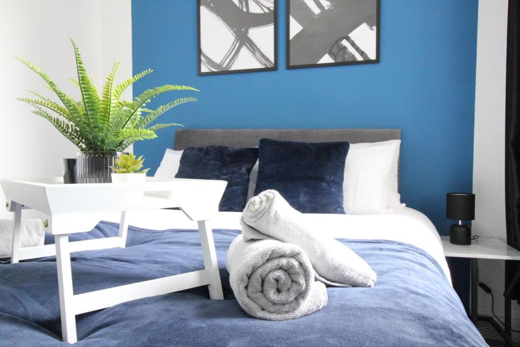 伍尔弗汉普顿Amazing - 1BDR - Free Street Parking的一间拥有蓝色墙壁的卧室和一张带毛巾的床
