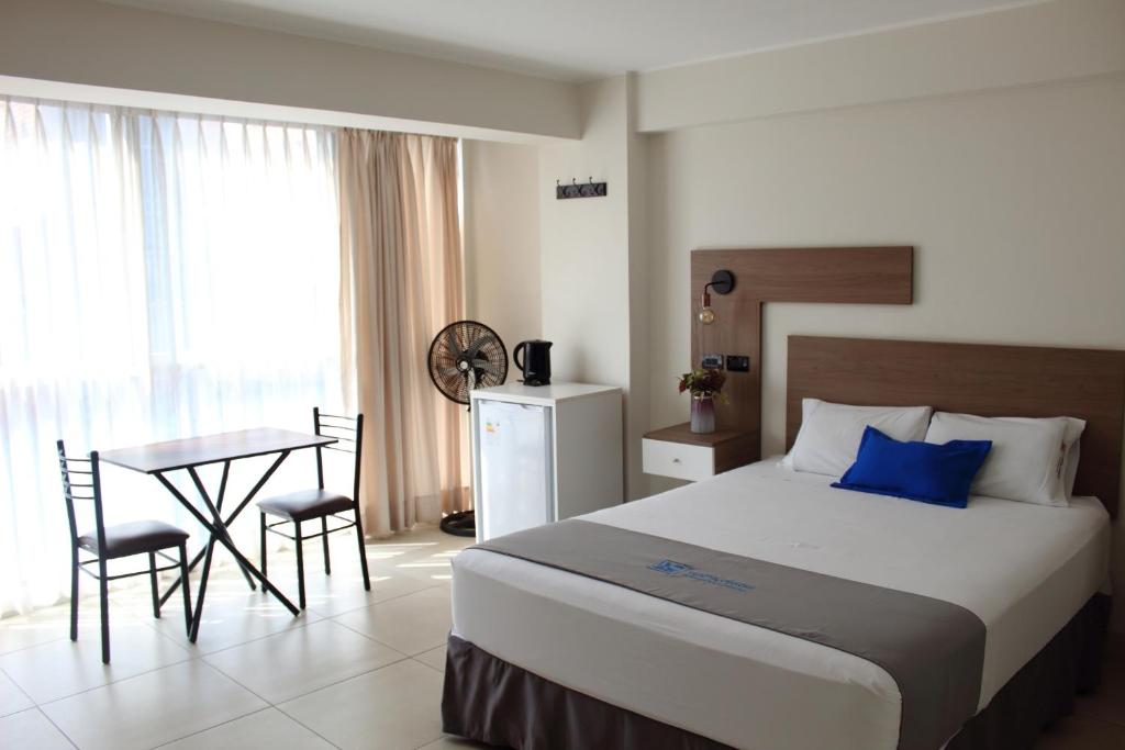 上钦查Hotel Luxotel Chincha的一间卧室配有一张床和一张桌子及椅子
