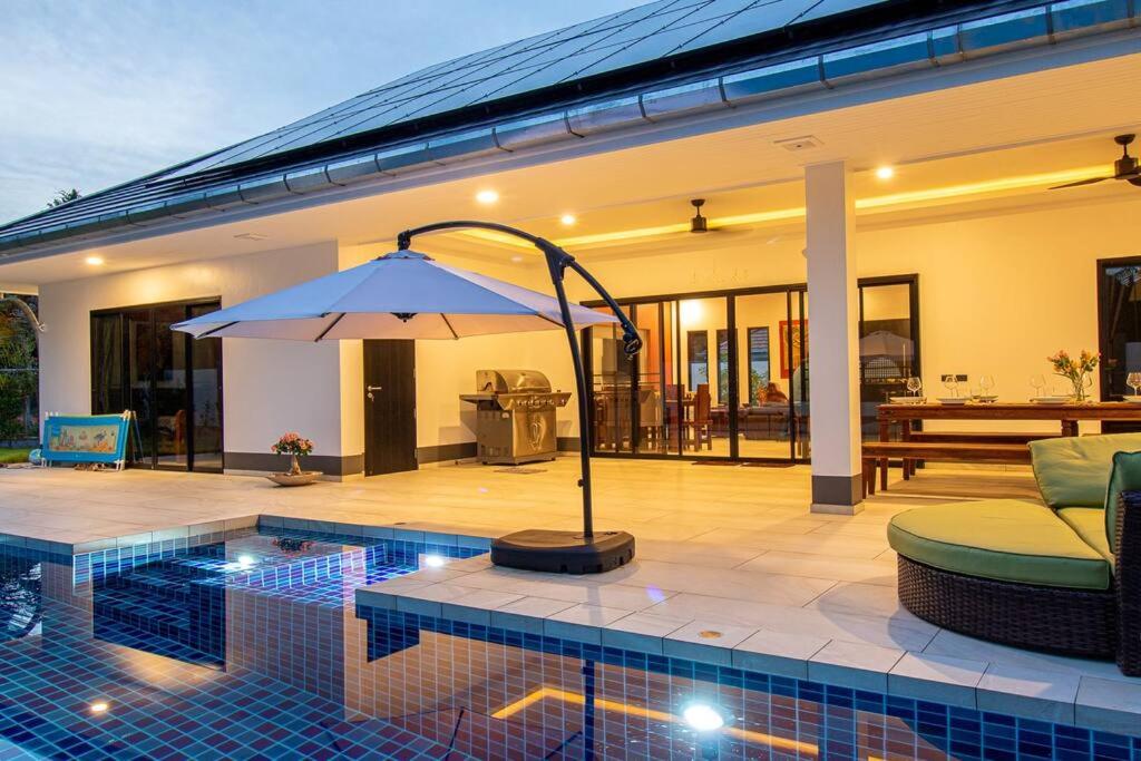 奥南海滩RUSARDI Poolvilla Ao Nang - new Villa 4 Bedrooms 4 Bathrooms, 10m Pool的一座房子旁带遮阳伞的游泳池