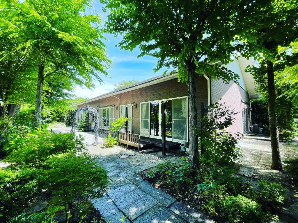 北斗市HOKUTO SATOYAMA BASE的一座带庭院的房屋,前面有树木