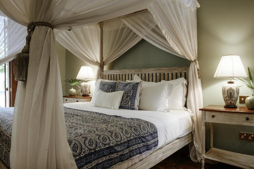 科伦坡玛尼帕西度假酒店的卧室配有带白色枕头的天蓬床