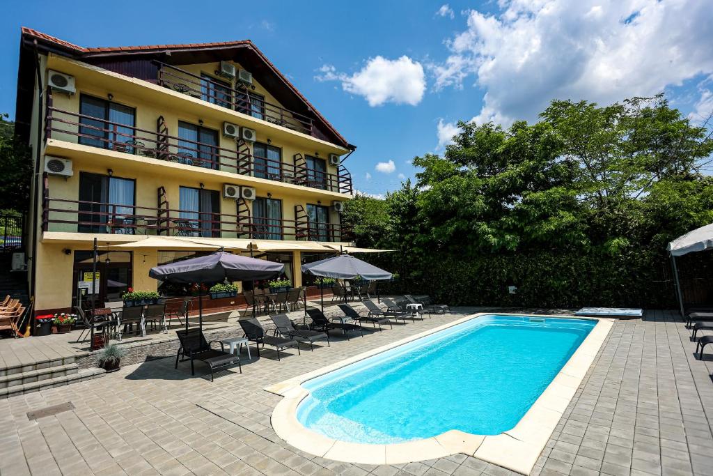 埃尔埃尼塔Casa Celestin的酒店前的游泳池配有椅子和遮阳伞