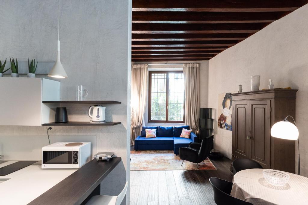 维罗纳Rosa Luxury Apartment的厨房以及带蓝色沙发的客厅。