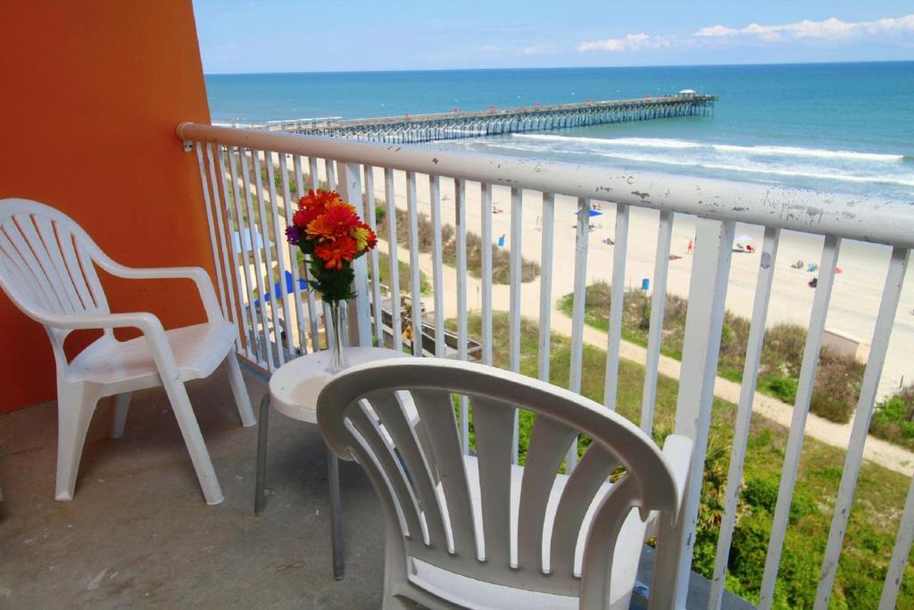 默特尔比奇巴港酒店的阳台配有两把椅子、花瓶和海滩