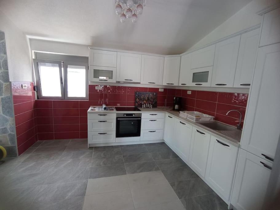 多布拉沃达Villa Mona Liza的厨房配有白色橱柜和红色墙壁