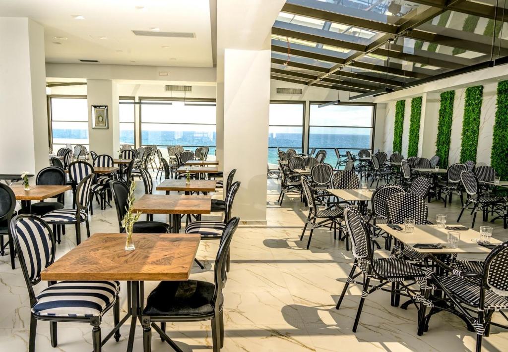 米蒂利尼Mythical Coast Wellness Retreat的一间空餐厅,配有桌椅,享有海景