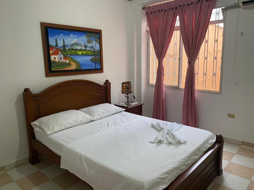 图卢阿Hotel Los Corales Tulua的一间卧室配有一张带白色床单的床和一扇窗户。