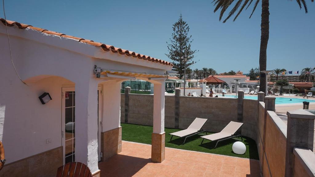 马斯帕洛马斯BUNGALOW LOS ARCOS的一个带两把躺椅的庭院和一个游泳池