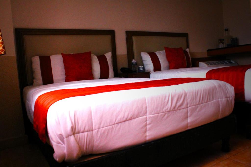 蒙特雷El Regio的一间卧室配有两张红色和白色床单