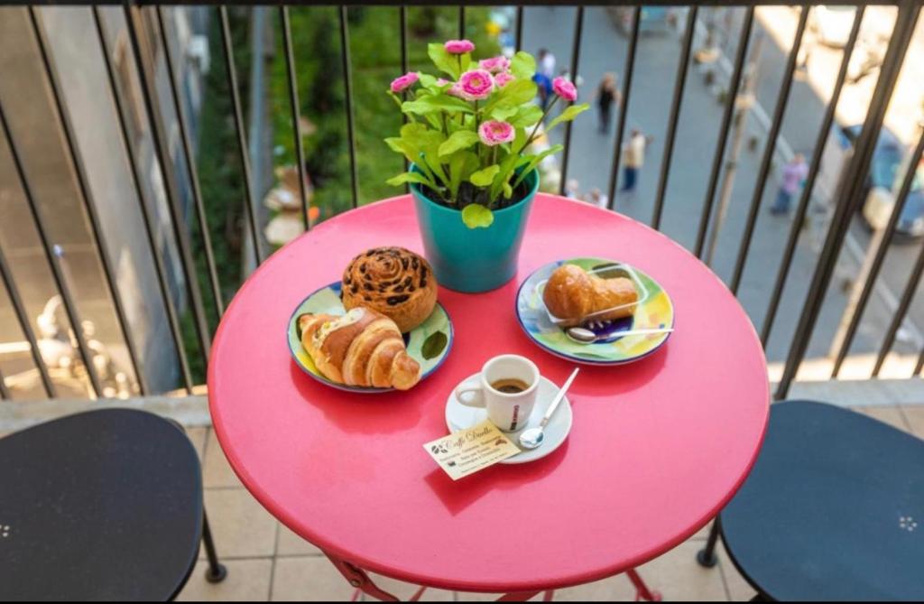 那不勒斯Apartment NAPOLI MARADONA的粉红色的桌子,上面有糕点,花瓶