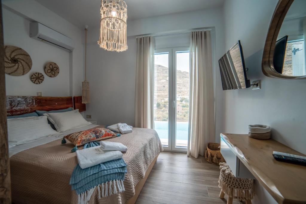 基斯诺斯Epithea Suites Kythnos 1 με ιδιωτική πισίνα的一间卧室配有一张床、一张书桌和一个窗户。