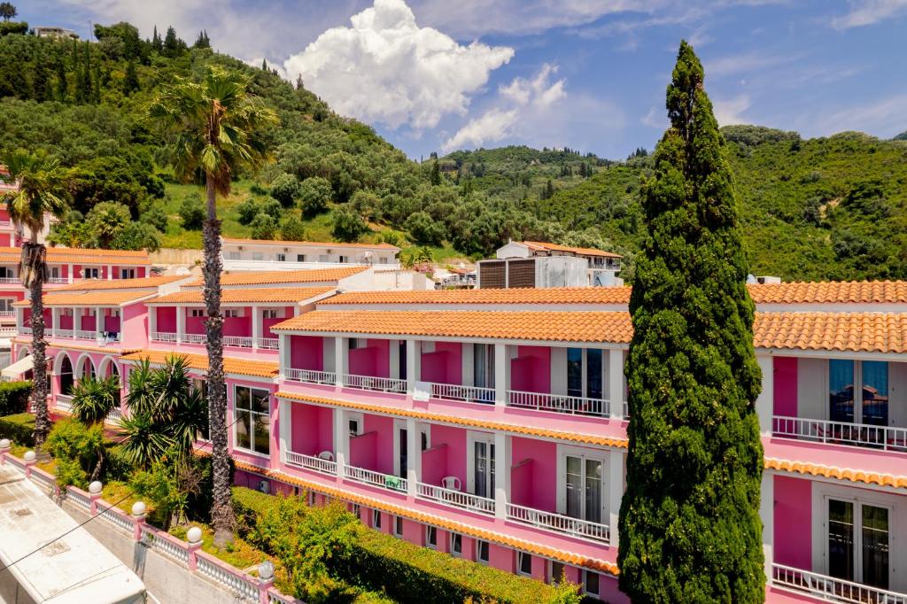 阿齐欧斯·贡多斯粉红宫海滩度假酒店的一排种有棕榈树的粉红色建筑