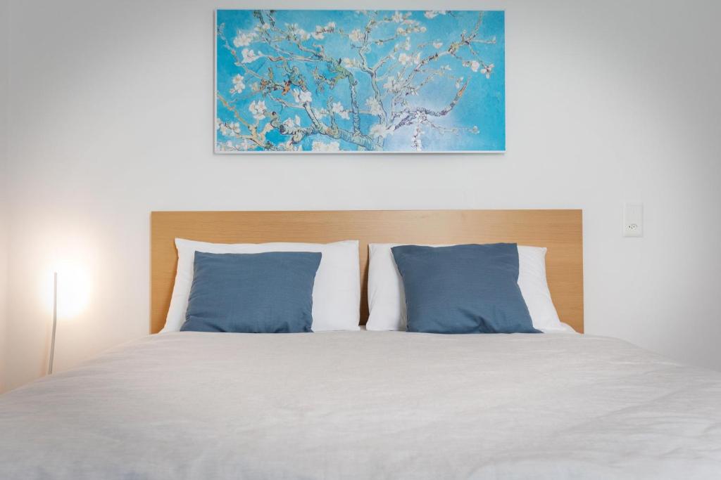 卢加诺Easy flat Vezia, indipendent entrance, free parking的一张带蓝色枕头的床和上面的绘画