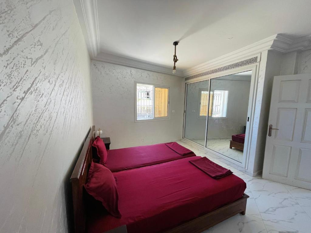 Ghār al MilḩSeaside Guest House的一间卧室配有红色的床和镜子