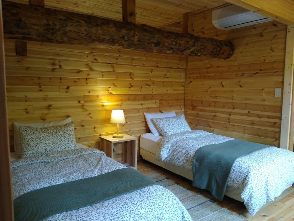 饭山市Robin's Lodge的木墙客房的两张床