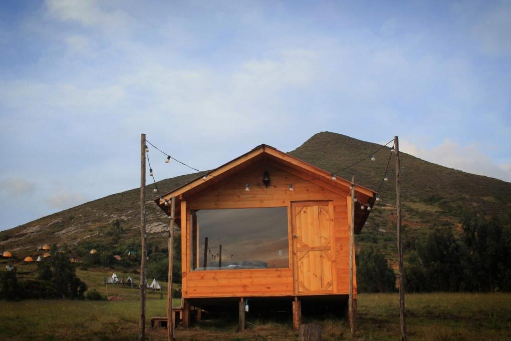 瓜塔维塔Camping & Cabaña San Francisco - Guatavita的田野上带大窗户的小房子