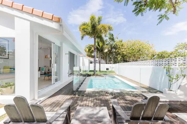 努萨角Poinciana House—Luxury Noosa Retreat close to Beach的一座带游泳池和带椅子的庭院的房子