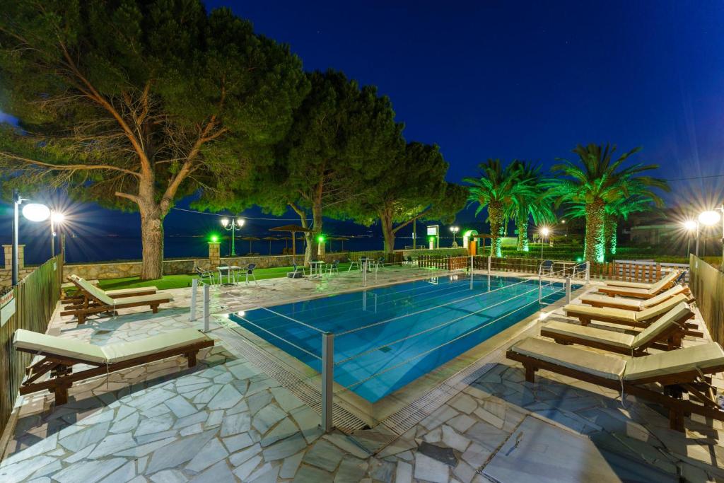埃拉蒂尼Nefeli Studios的游泳池,晚上有椅子和树木